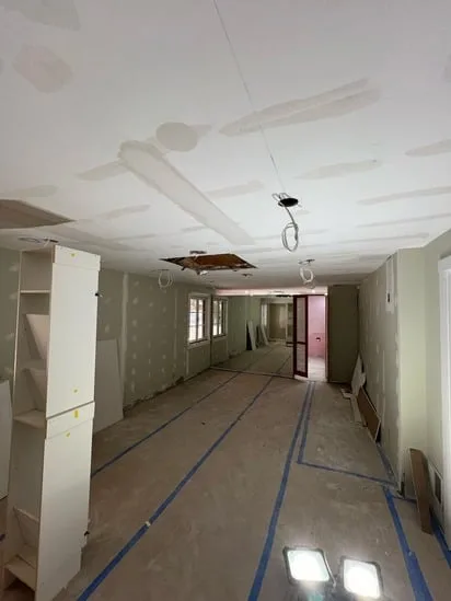An interior room view highlighting dry joint compound on taped ceiling seams, prepared for the final skimming coat.